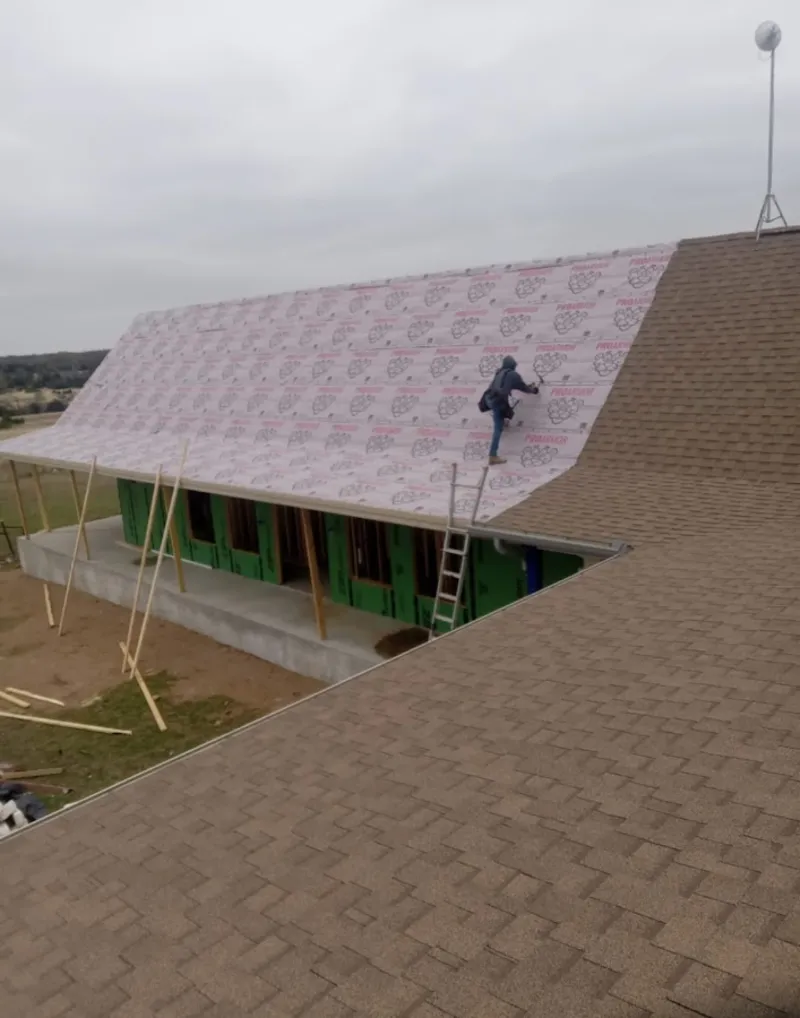 Worker preparing underlayment for a metal roof installation in Joshua